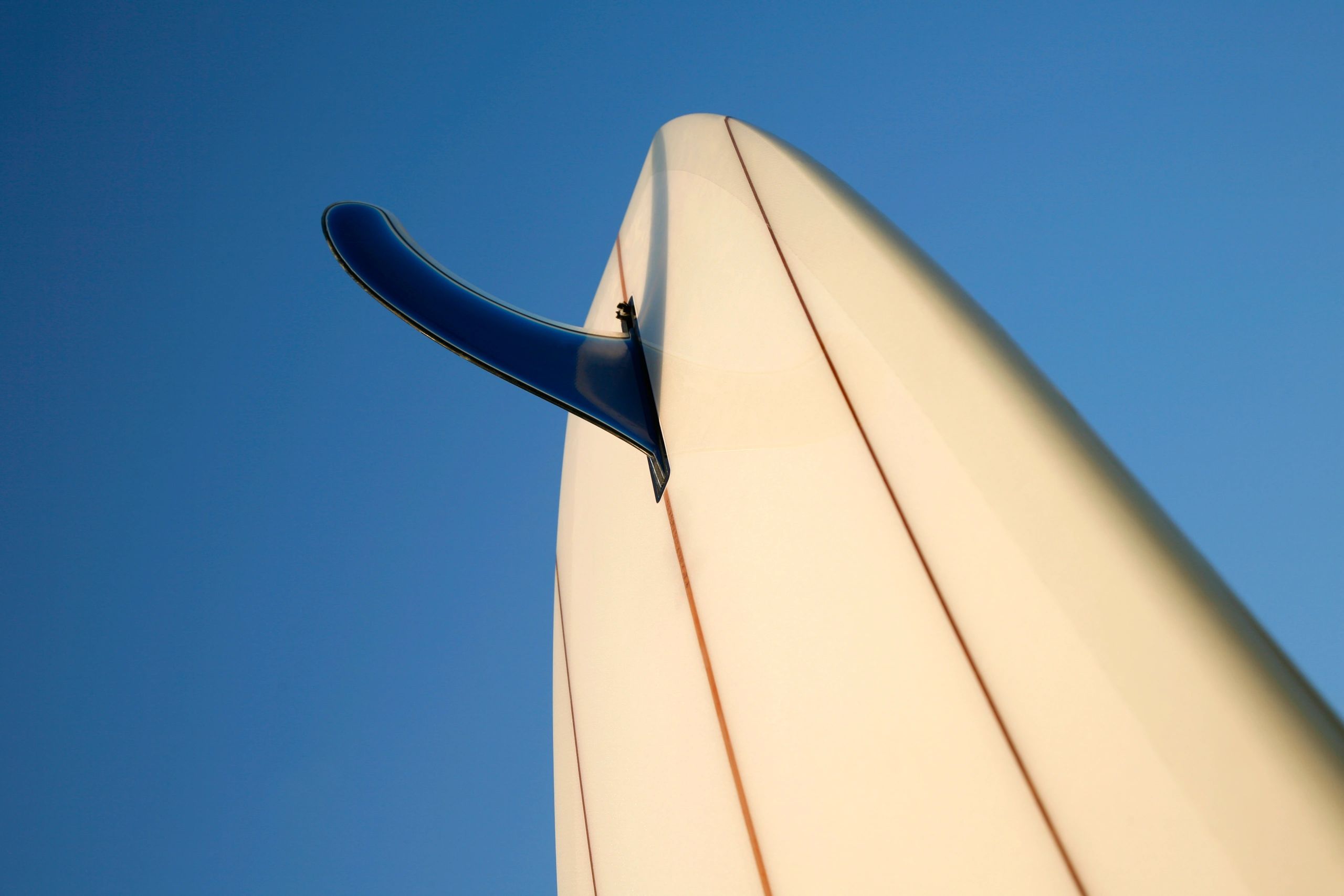 Close-up surfboard fin against a bright sky