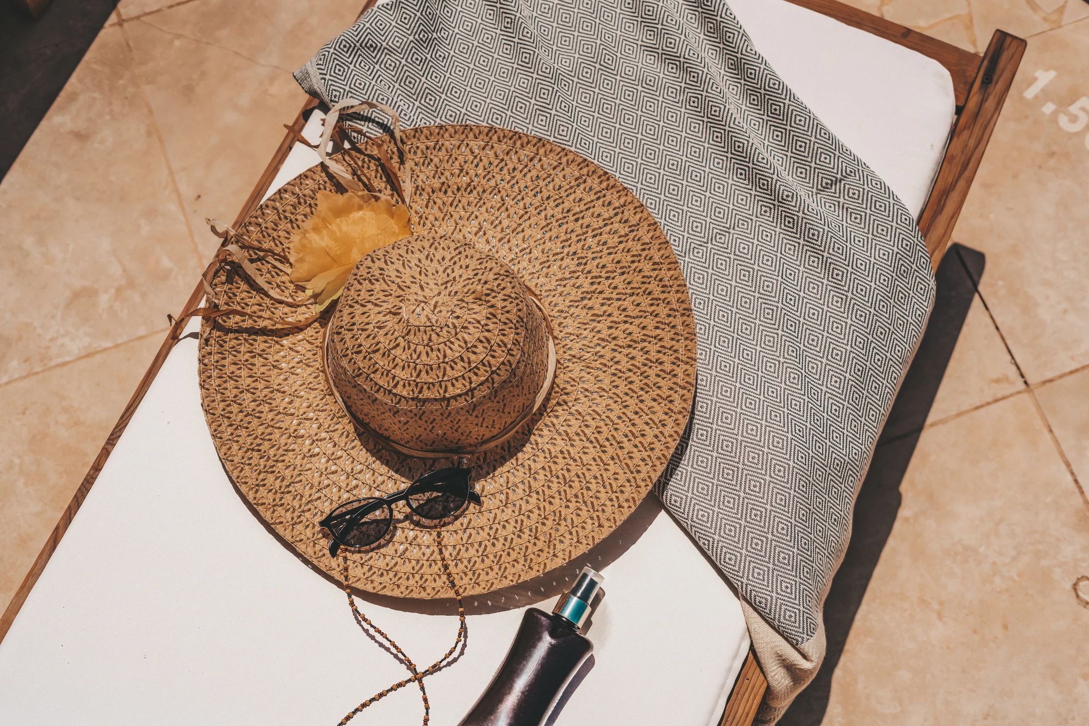 Summer weekend essentials laid out: hat, sunglasses, and sunscreen