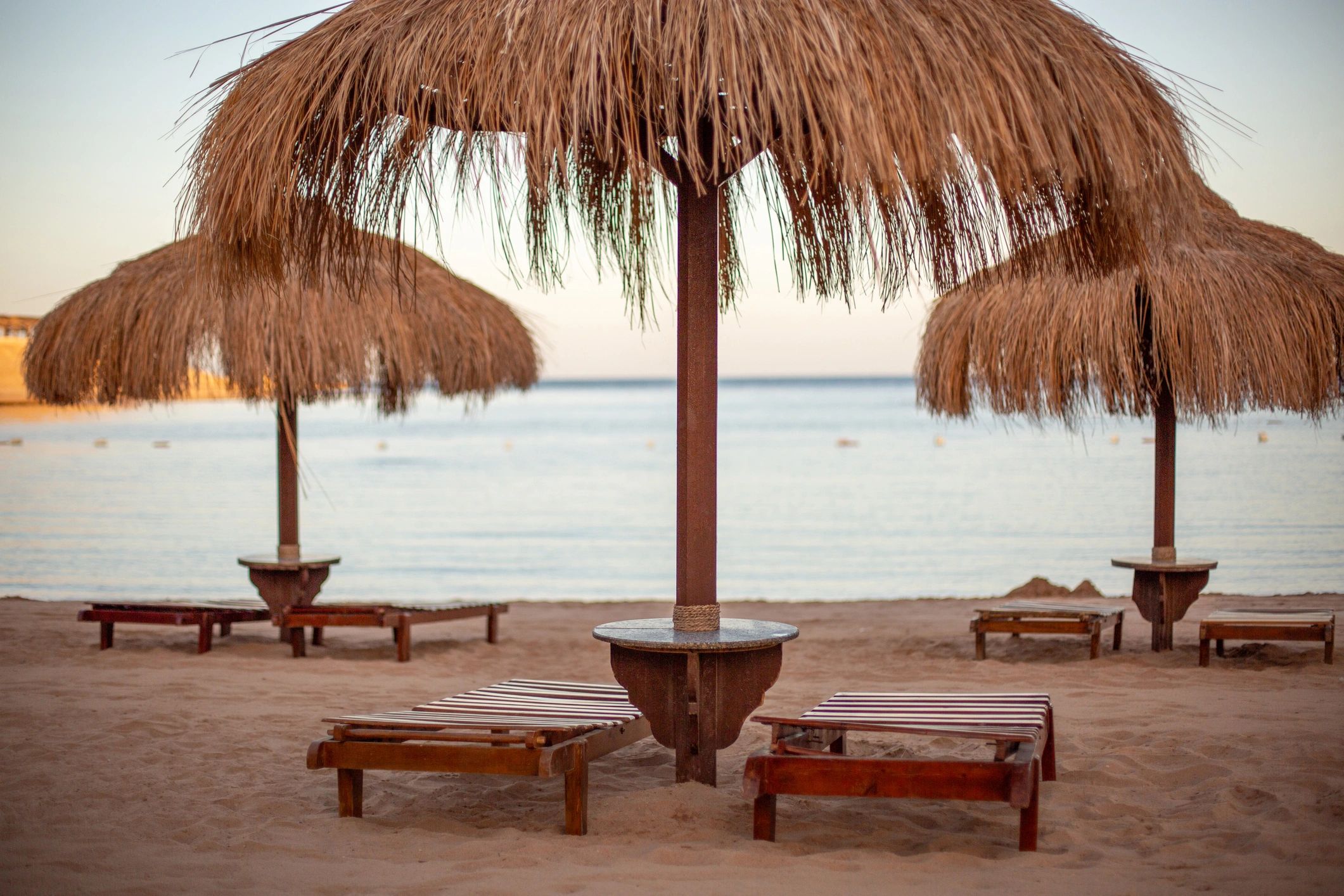 Beach umbrella and lounge chairs set up on an empty shoreline